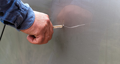 a person using a key to scratch the side of a car