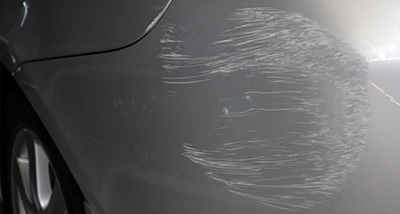 an area of scratches from a collision on a silver car