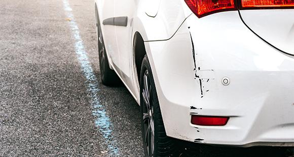 a scuffed bumper of a white car