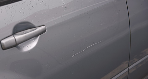 a keyed scratched on the door of a silver car