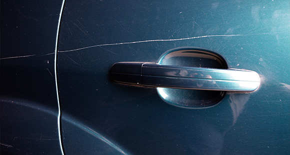 a blue car with a long scratch along the side of the door