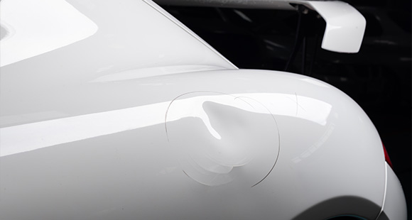 a white sports car with a circular dent in the side