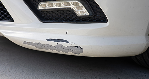the front bumper of a white car with the paint peeling off 