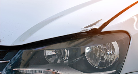 a dent on the bonnet of a silver car
