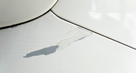 the body of a white car with a scratched area with the paint removed